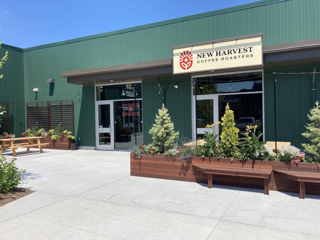 an image of the outside of New Harvest coffee roasters in providence. It is a green building, with an outdoor patio and some decorative plants.
